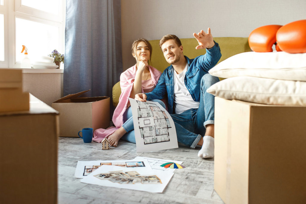 casal sentado e planejando seu novo lar. Imagem ilustrativa para texto comprar um apartamento na planta.