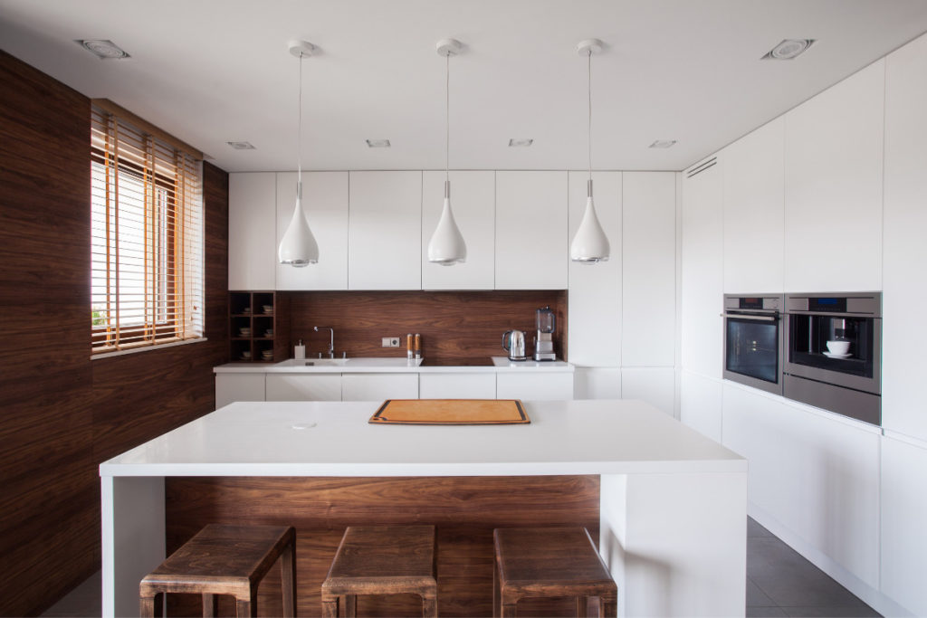 cozinha branca com detalhes em madeira e luminárias.